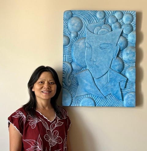 Hoï Wong, thérapeute en réflexologie et shiatsu, devant un bas-relief de son cabinet à Franconville